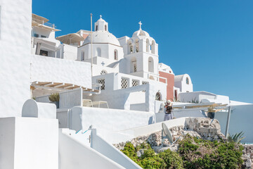Tourist woman on vacation in Thira walking on stairs. Person in white dress is visiting the famous...