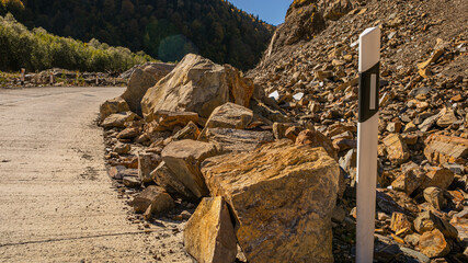 Fototapeta na wymiar Large boulders scattered across a road in a landslide, depicting natural disaster impact and roadblock concept