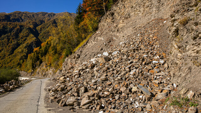 A rockslide has covered a mountain road with debris in autumn, showcasing natural hazards and road safety issues