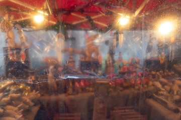A market stall, seen through rain spattered protective plastic sheeting, produces a dreamy,...