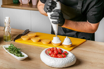 A chef is piping cream onto tart shells in a kitchen setting, depicting a concept related to baking...