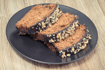 Homemade pastry made of zucchini with nuts and raisin on black plate. Wooden background
