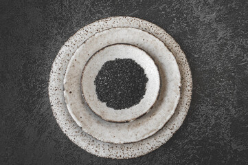 Coal salt. Black Himalayan salt. Russian Thursday rye salt. Top view of handmade kraft clay plates...