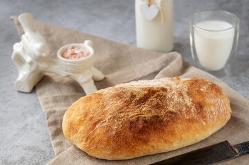 Craftsman sliced toast bread with butter on a wooden cutting board and milk. Simple breakfast on a gray concrete background. Close-up view