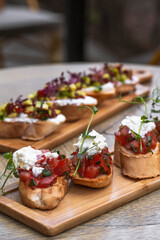 Bruschetta with tomatoes, feta cheese and herbs on wooden board . mozzarella and arugula. Canape