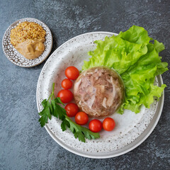 Homemade jellied meat with mustard and horseradish on the table. Aspic. Homemade jelly with mustard, tomatoes and garlic on the table. Kholodets, traditional Russian food