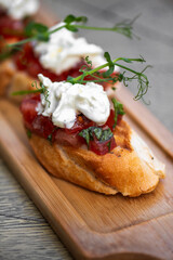Bruschetta with tomatoes, feta cheese and herbs on wooden board . mozzarella and arugula. Canape