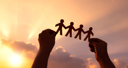 Teamwork and relations concept. woman holding human paper chains at sunrise. People are connected. Concept of human role.  teamwork, family home, society, social network, and people - obrazy, fototapety, plakaty