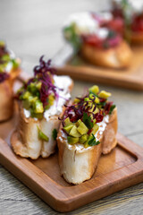 Canapes with avocado, mozzarella cheese and sauce on wooden board . bruschetta