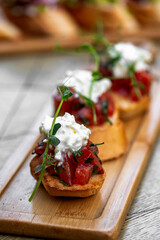Bruschetta with tomatoes, feta cheese and herbs on wooden board . mozzarella and arugula. Canape