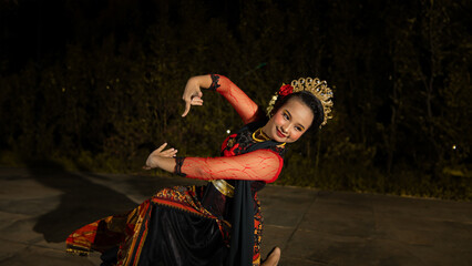 a Balinese dancer wearing gold jewelry and dancing with confidence on the stage
