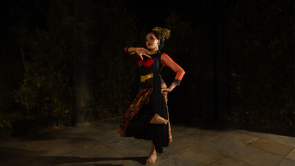 A Sundanese dancer wears a beautiful sparkling red costume and dances with a passionate expression