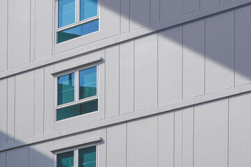 Sunlight and shadow on surface of glass windows with geometric pattern on concrete wall of modern building, Minimal exterior architecture background in street style