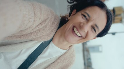 Positive mature woman smiling and speaking on camera during video call outdoors on city street. POV vertical format clip - Powered by Adobe