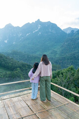 Fototapeta na wymiar Mother and daughter standing on the mountain and enjoy the view.