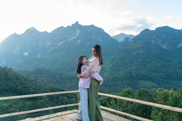 Mother and daughter standing on the mountain and enjoy the view.