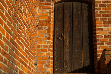 An antique wooden door with a metal ring framed in brickwork