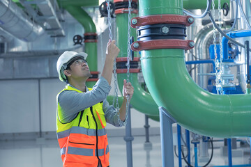 worker pulling chain  for close valve. Engineer work in chiller plant room.