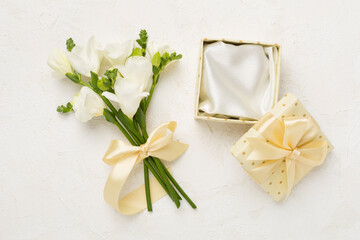 Open gift box, with fresia flower concrete background, top view