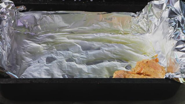 Women's hands place marinated chicken wings in spices on Olga for baking. Medium plan.