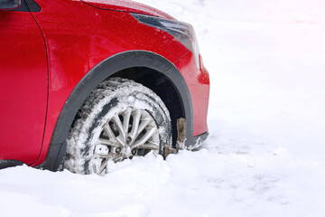 Wheel stuck in snow, snowfall in the city. Snow covered car wheel, close up.