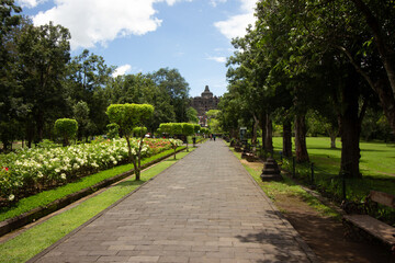 A serene pathway leading to an ancient temple in a lush park setting.