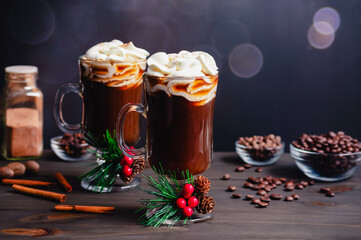 Spiced Christmas Coffee Topped with Whipped Cream: Two glass mugs of freshly brewed spiced coffee with Christmas decorations and ingredients