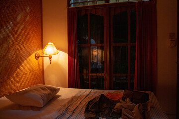 A cozy bedroom interior at night with a warm light and a neatly made bed.