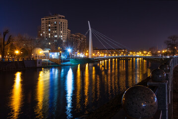 Fototapeta premium Scenic view of the Kharkiv river with a pedestrian bridge and embankment in the city on an autumn evening