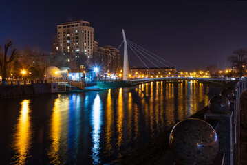 Scenic view of the Kharkiv river with a pedestrian bridge and embankment in the city on an autumn evening