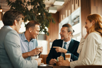 Business colleagues talking during a coffee break at a cafe - obrazy, fototapety, plakaty