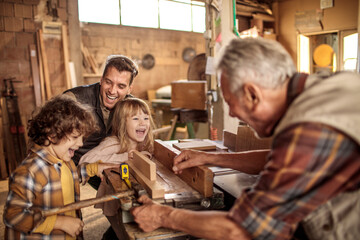 Father and children with grandfather in a woodworking workshop