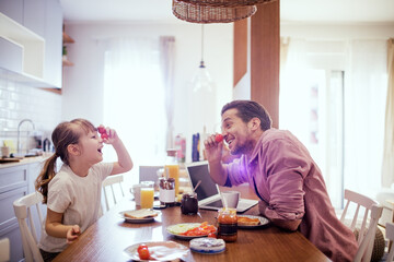 Father and daughter enjoying a playful breakfast in a cozy kitchen