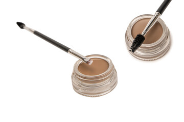 A brow pomade in blonde shade with brush isolated on a white background.