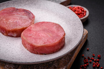 Round shape steaks of raw juicy tuna with salt and spices