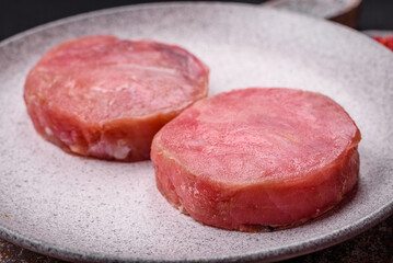 Round shape steaks of raw juicy tuna with salt and spices