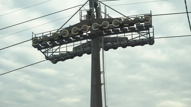 Support of ski lift with rotating rollers. Cable car passes by the support tower. Cable car support tower with cable car mechanism and gears