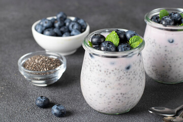 Chia pudding with blueberry and mint in glass jars on gray background, Healthy food