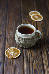 A light ceramic tea mug with dried orange slices on a wooden table. Selective accent.
