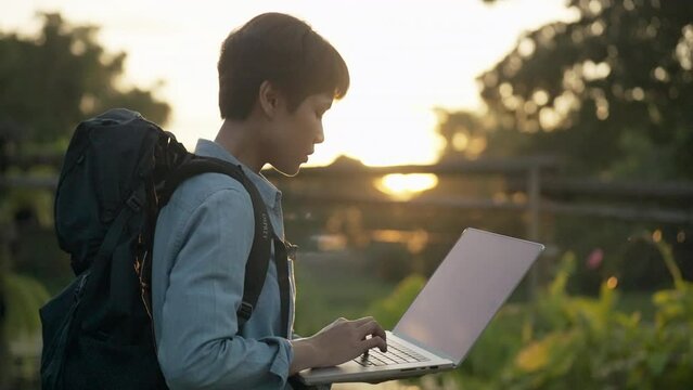 portrait of a beautiful asiatic solo travel Asian female model walking with his backpack during a sunset in slow motion, and working at the laptop computer