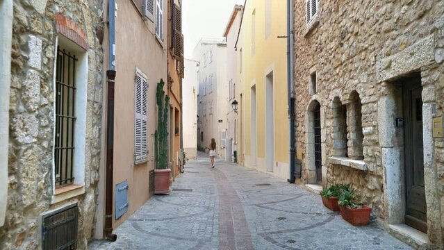 Young woman walking on the streets surrounded by colorful ancient buildings in Antibes, France