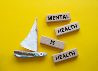 Mental Health symbol. Wooden blocks with words Mental Health is Health. Beautiful yellow background...