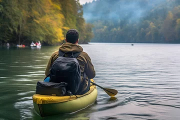 Foto op Canvas Young man is paddling a canoe on forest river. © Degimages
