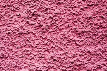 Home facade texture. Red rough surface. Grunge grain. Crushed rocks in the wall. Exterior home decoration. Stucco wall pattern. Pink color retro design. Noisy design background.