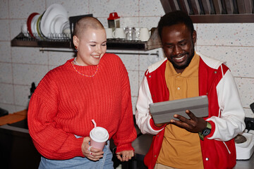 Diverse group of young people sitting at table in college dorm together and chatting joyfully