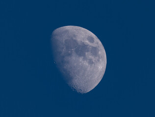 half waxing gibbous moon on dark blue sky