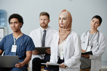 Diverse group of doctors sitting in audience at educational seminar and listening to lecture on medicine