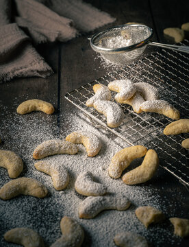frisches, selbstgebackenes Weihnachtsgeb&auml;ck, Kekse, Vanillekipferl mit Puderzucker bestreut auf dunklem moody Hintergrund.