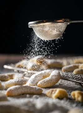 frisches, selbstgebackenes Weihnachtsgeb&auml;ck, Kekse, Vanillekipferl mit Puderzucker bestreut auf dunklem moody Hintergrund.
