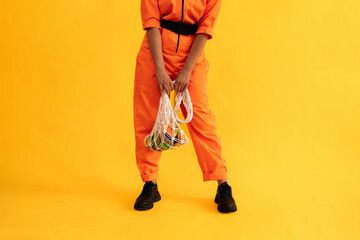woman wear modern orange overalls with eco string bag and colored gingerbread cookies on bright...